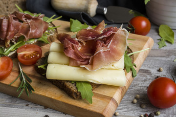 Sandwich with black bread, ham, cheese and vegetables, healthy breakfast