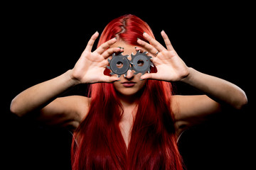 Fototapeta premium Portrait of beautiful girl with circular saw blade. Bretty naked woman, long red hair, nude body, sawblade, dark background. Female and sharp stainless steel disc