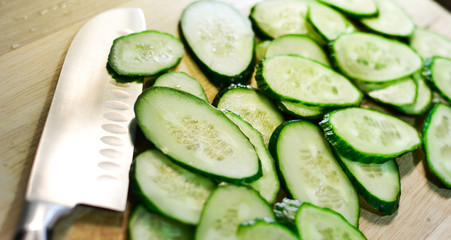 chef's knife or thin slices of cucumbers on a wooden table