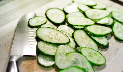 chef's knife or thin slices of cucumbers on a wooden table