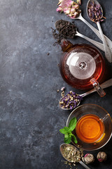 Tea cup, teapot and assortment of dry tea in spoons © Evgeny Karandaev