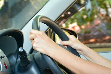 Hand of human holding black steering wheel in a car