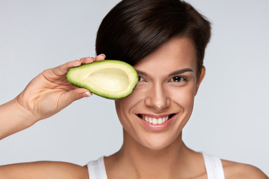 Skin Care And Beauty. Beautiful Woman Holding Avocado Near Face