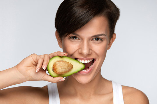 Nutrition. Beautiful Smiling Woman Biting Organic Green Avocado