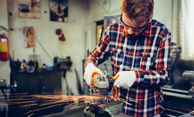 Young manual worker working with grinder