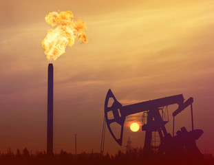 Industrial landscape. Gas torch on a background of sunset sky. Oil Field.