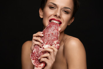 Eating Meat. Beautiful Woman Biting Raw Red Beef Steak Meat
