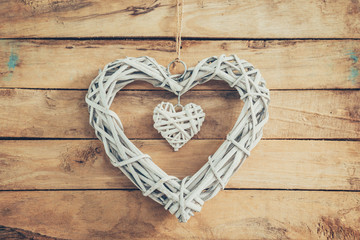 Two wooden rustic decorative hearts hanging on vintage wooden ba