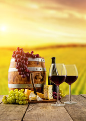 Verres à vin rouge servis sur des planches de bois, vignoble en arrière-plan
