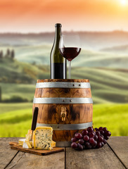 Red wine served on wooden barrel, vineyard on background