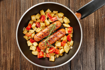 Grilled sausages in pan with fresh rosemary and grilled potatoes