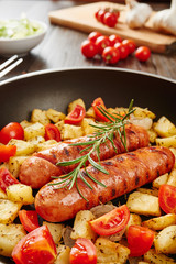 Grilled sausages with fresh rosemary and grilled potatoes - ingredients in background