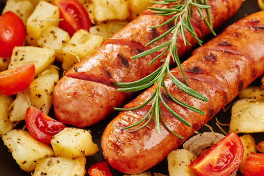 Grilled sausages with fresh rosemary and grilled potatoes close up