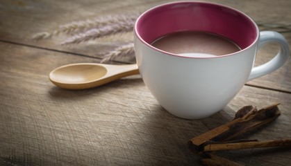 Hot chocolate cup and cinnamon sticks on wooden table