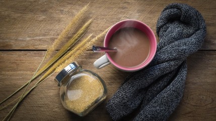 Hot chocolate cup, sugar jar and scarf on wooden table