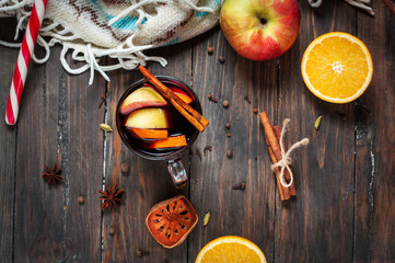Hot mulled wine with spices, apple and orange on wood