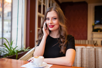 Beautiful girl drinking coffee and talking on the phone