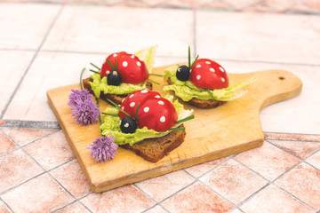Sandwich in form of ladybird beetles made of fresh tomato, salad and bread. Funny children breakfast 