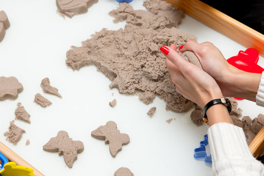 woman hands making a figure from wet sand