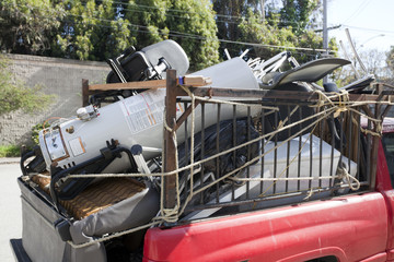 Rear of red pickup truck filled with household junk. Horizontal.