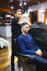 hairdresser makes hairstyle for a young man