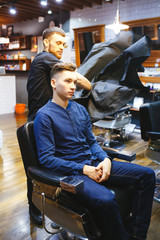 hairdresser makes hairstyle for a young man