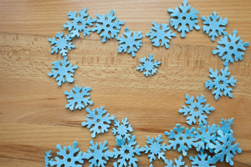 Heart of blue snowflakes on a wooden background