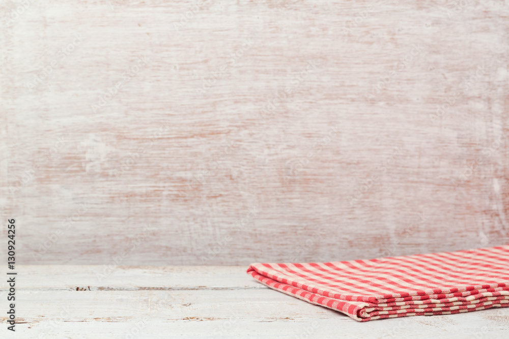 Wall mural empty wooden table with checked tablecloth over rustic wall. background for product montage display