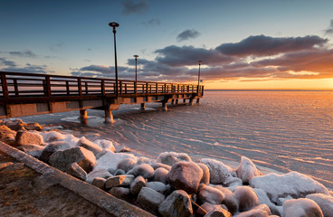 A wooden pier and frozen Bay of Puck at sunset time. Poland. Europe.