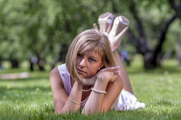 Obraz premium Young blond woman in white dress lying on the grass 