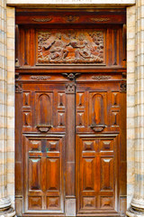 Obraz premium Antique wooden double door of a church. Detailed carpenter work, wood carvings in geometric shapes and a relief above the entrance in the door frame.