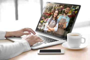 Photo sur Plexiglas Fleuriste Video call and chat concept. Modern communication technology. Woman ordering flowers delivery online via laptop.