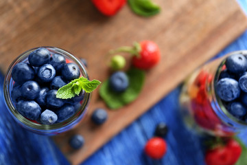 Glass jar with fruits and berries on wooden background, top view