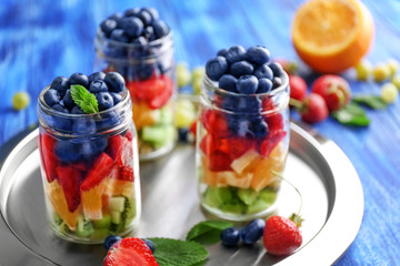Glass jars with fruits and berries on metal tray