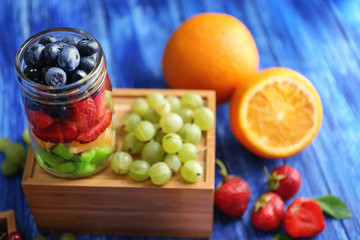 Glass jar with fruits and berries on wooden box