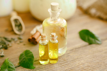 Bottles with tea oil on wooden background
