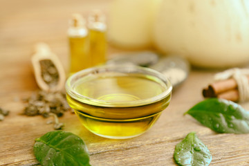 Glass bowl with tea oil on wooden background
