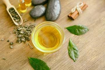 Glass bowl with tea oil on wooden background