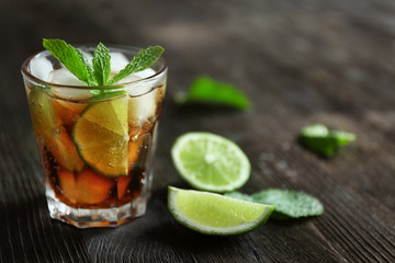 Glass of cocktail with ice and mint on wooden table closeup