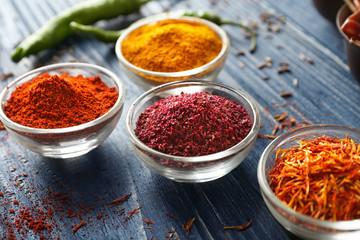 Aromatic spices in glass bowls on blue wooden background
