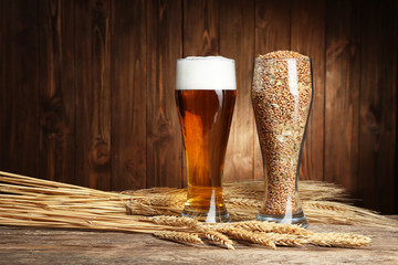 Glasses of beer and seeds with spikes on wooden background