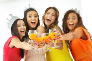 Beautiful girls with cocktails on light background
