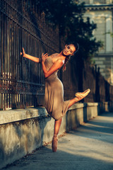 Fototapeta na wymiar Young beautiful ballerina dancing on the sidewalk