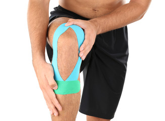 Physio tape applied onto male knee, isolated on white