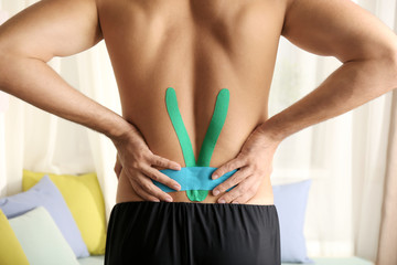 Male lower back with applied physio tape indoors