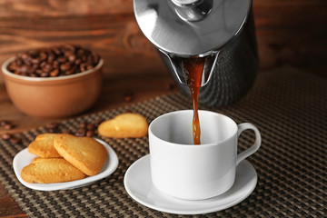 Fresh coffee pouring from pot into cup