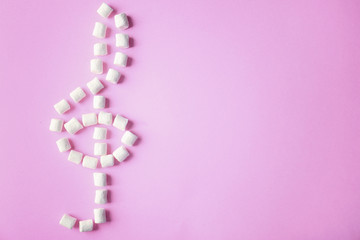 Treble clef made of marshmallow on pink background