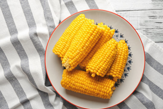 Plate with tasty boiled corncobs on kitchen table, top view