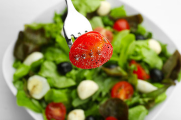 Slice of fresh tomato impaled on fork