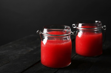 Jars with watermelon smoothie on dark wooden table